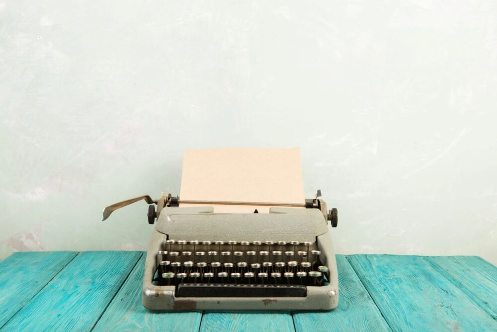 typewriter with a blank piece of paper on a blue wooden table
