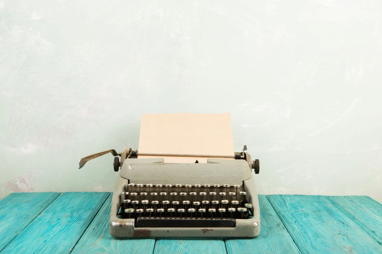 typewriter with a blank piece of paper on a blue wooden table
